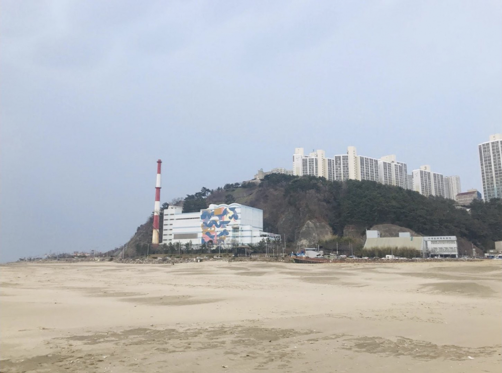 부산 다대포 해안에서 바라본 과거 김복동의 가게가 있던 자리에는 높은 굴뚝의 다대환경사업소가 들어서 있다. (사진 제공: 송원근)