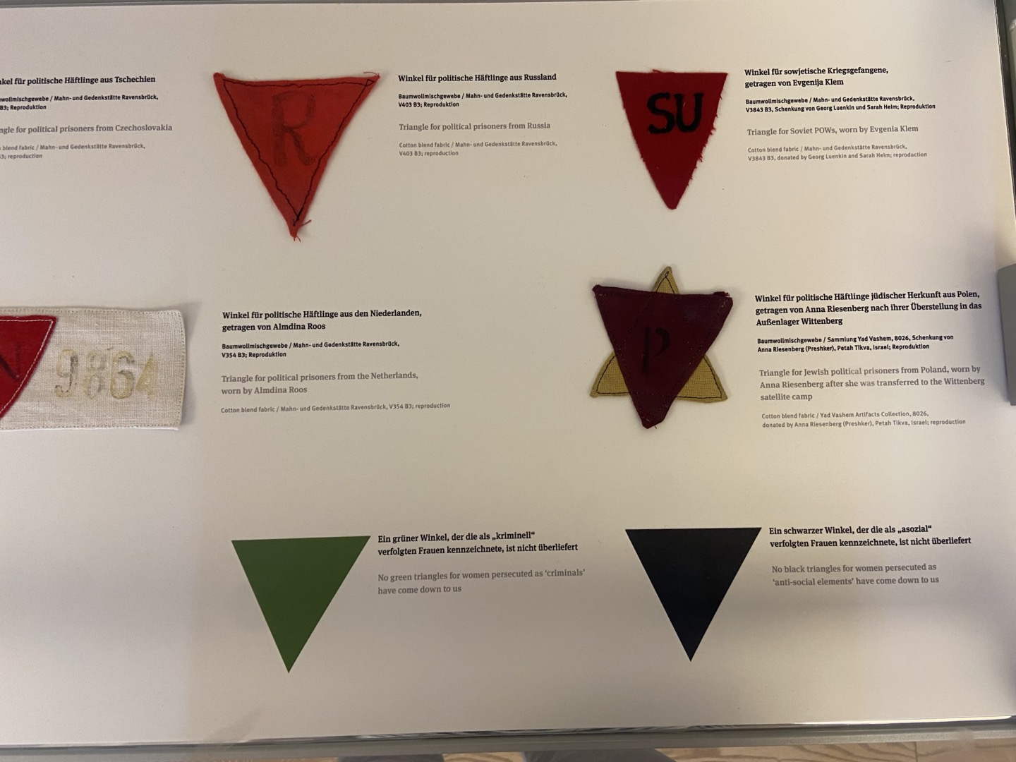 [Photo 13] Prisoner markings. The black inverted triangle on the bottom right was for asocials, and the red inverted triangle on the top left for political prisoners. The red inverted triangle with an R inside was used to identify Russian political prisoners, and the one with SV to the right of it to identify Soviet prisoners. The green inverted triangle in the lower left represented criminals, and the yellow and black triangle forming a star shape in the middle right symbolized Polish Jews. Polish Jewish political prisoners were identified with this marking. 