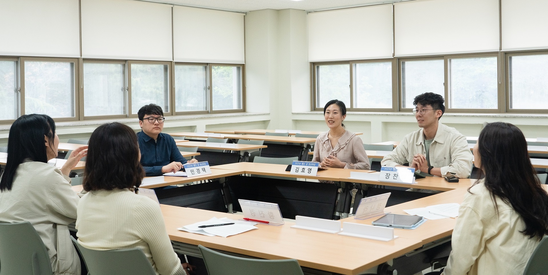 2023년 웹진 결 청년좌담 현장. ㅁ자로 놓인 회의 탁자에 민경택, 김효영, 장찬영 명패를 둔 대담자 세 명이 나란히 앉아 있고, 그 맞은편에 사회를 맡은 일본군&lsquo;위안부&rsquo;문제연구소 학술기획팀 세 명이 등을 보인 채 앉아 이야기를 나누고 있다.