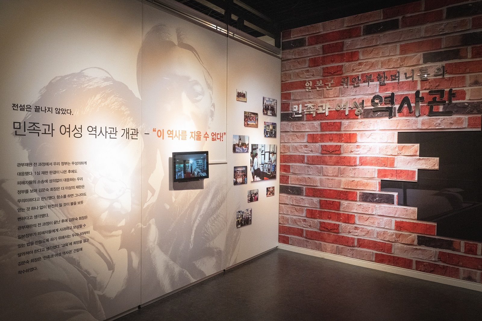 &lsquo;민족과 여성 역사관 개관 &ndash; &ldquo;이 역사를 지울 수 없다!&rdquo;&rsquo; 패널에 역사관 활동 사진들과 영상 모니터가 걸려 있고, 오른쪽에는 &lsquo;일본군 위안부 할머니들의 민족과 여성 역사관&rsquo; 간판을 붉은 벽돌 벽에 재현해 놓았다.