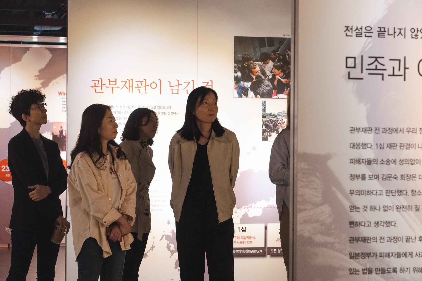 관람객들이 &lsquo;관부재판이 남긴 것&rsquo;과 &lsquo;민족과 여성 역사관&rsquo; 패널 사이에 서서 전시 설명을 듣고 있다.