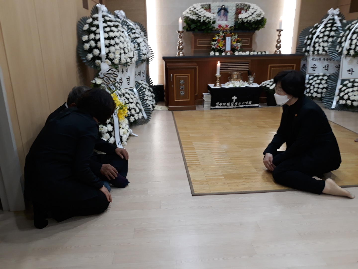 근조 화환이 늘어선 빈소에서 조문객과 맞은편에 앉은 사람들이 바닥에 무릎을 꿇고 서로 고개 숙여 인사를 나누고 있다. 안쪽에 김양주 할머니의 영정이 놓인 제단이 보인다.