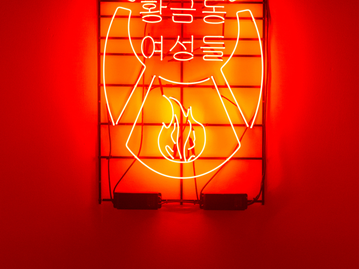 정유승 작가의 &lsquo;황금동 여성들&rsquo;이다. 붉은 빛으로 물든 벽에 5&middot;18 상징 모양과 불꽃을 본뜬 네온 안에 &ldquo;황금동 여성들&rdquo;이라는 글자가 빛나고 있다.