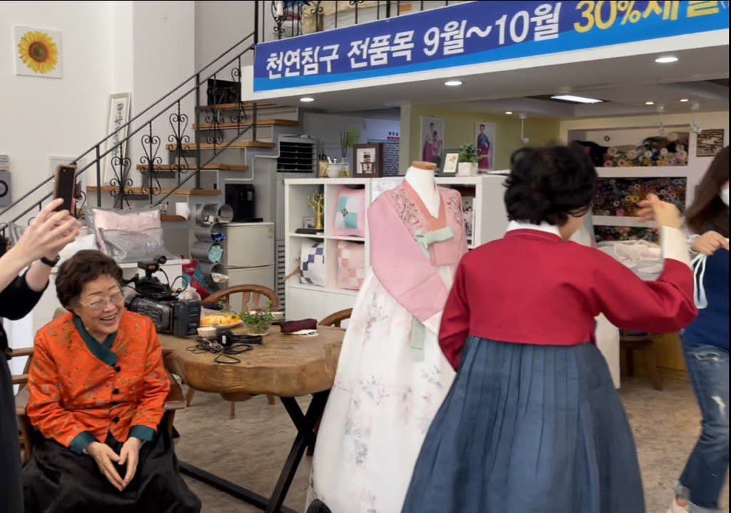카메라맨이 쓸 갓과 장신구를 챙기느라 바쁜 한복집 사장님과 직원. 그 옆에서 이용수님이 웃고 있다 © 김리라 