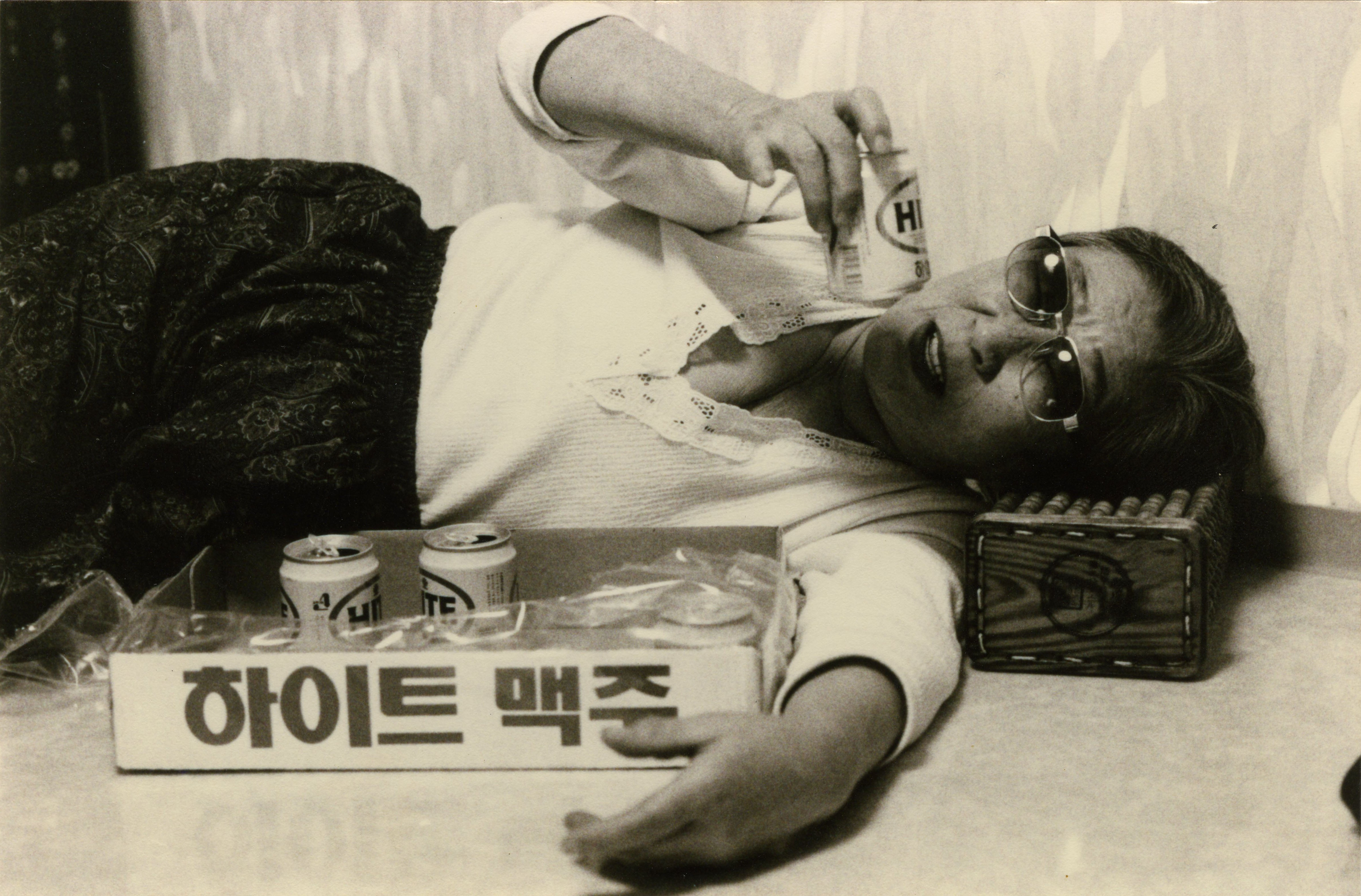 방 안에서 선글라스를 낀 채 누워서 맥주캔을 들어보이고 있다. (사진 제공 : 나눔의 집)